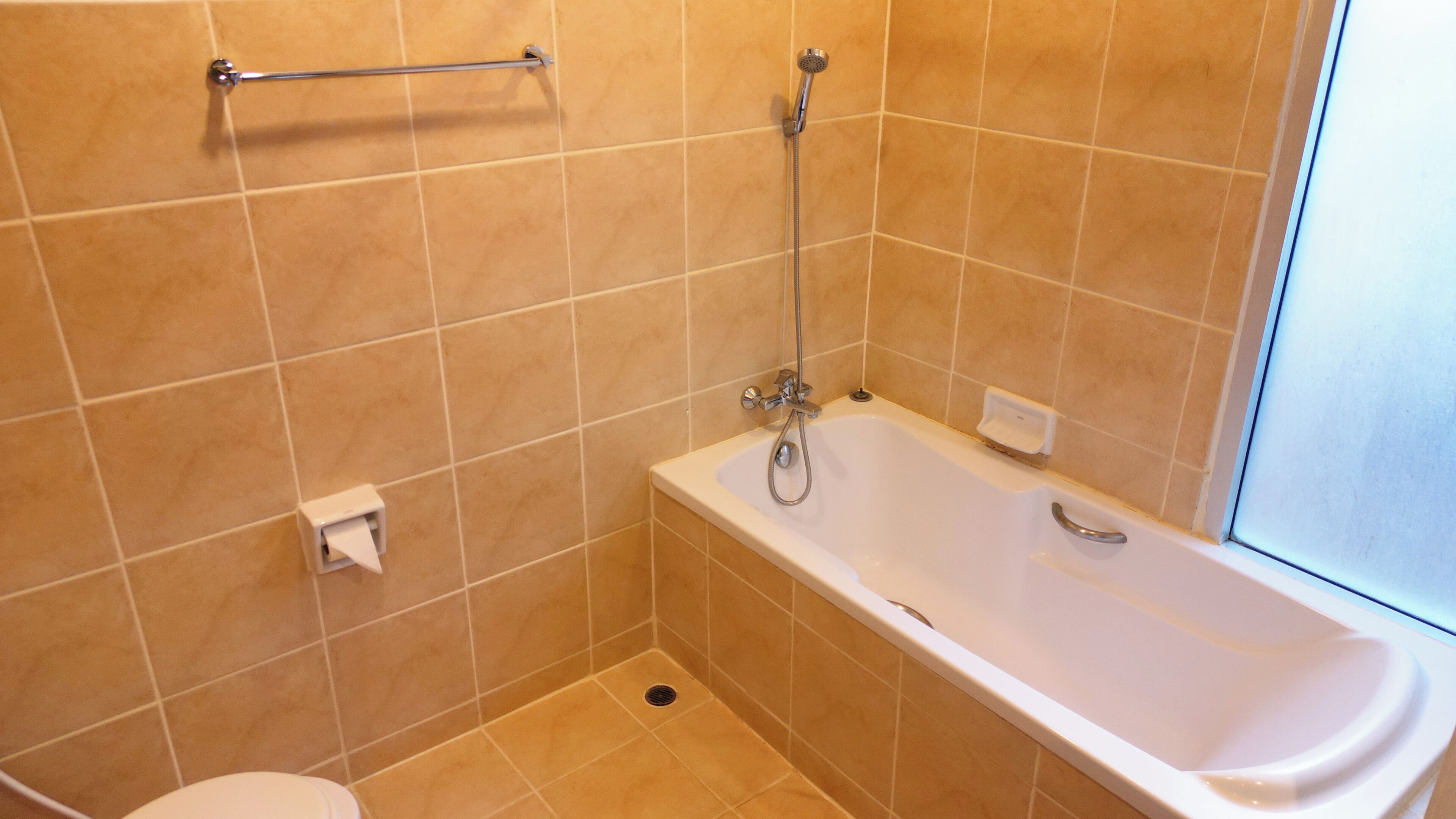 Et badeværelse med badekar, toilet og bruser.