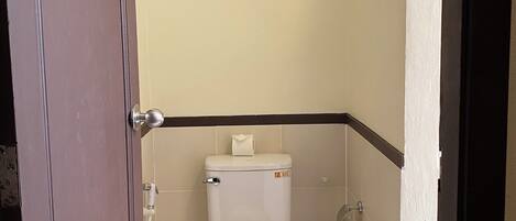 A small, compact bathroom with a toilet, a towel on the seat, and a framed picture on the wall.