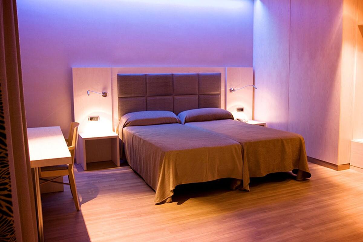 A bedroom with a bed, bedside tables, and a desk.
