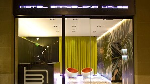 The entrance of a hotel with a reception desk, a green curtain, and a wall with a leaf pattern. - Hotel Barcelona House (Barcelona)