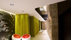 A modern interior with a hallway, green curtains, and two white chairs with red interiors. - Hotel Barcelona House (Barcelona)