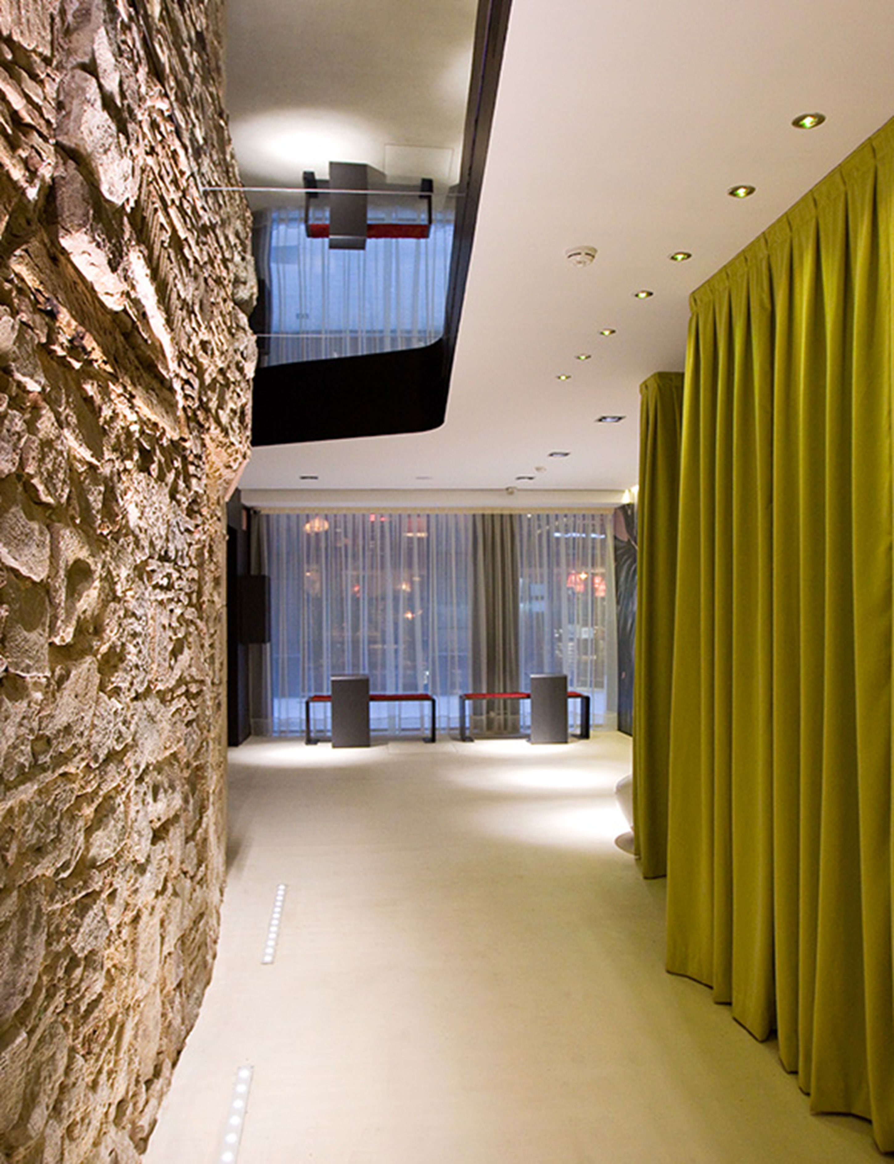 Ein modernes Interieur mit einer Steinwand, einem grünen Vorhang und einer Bank.