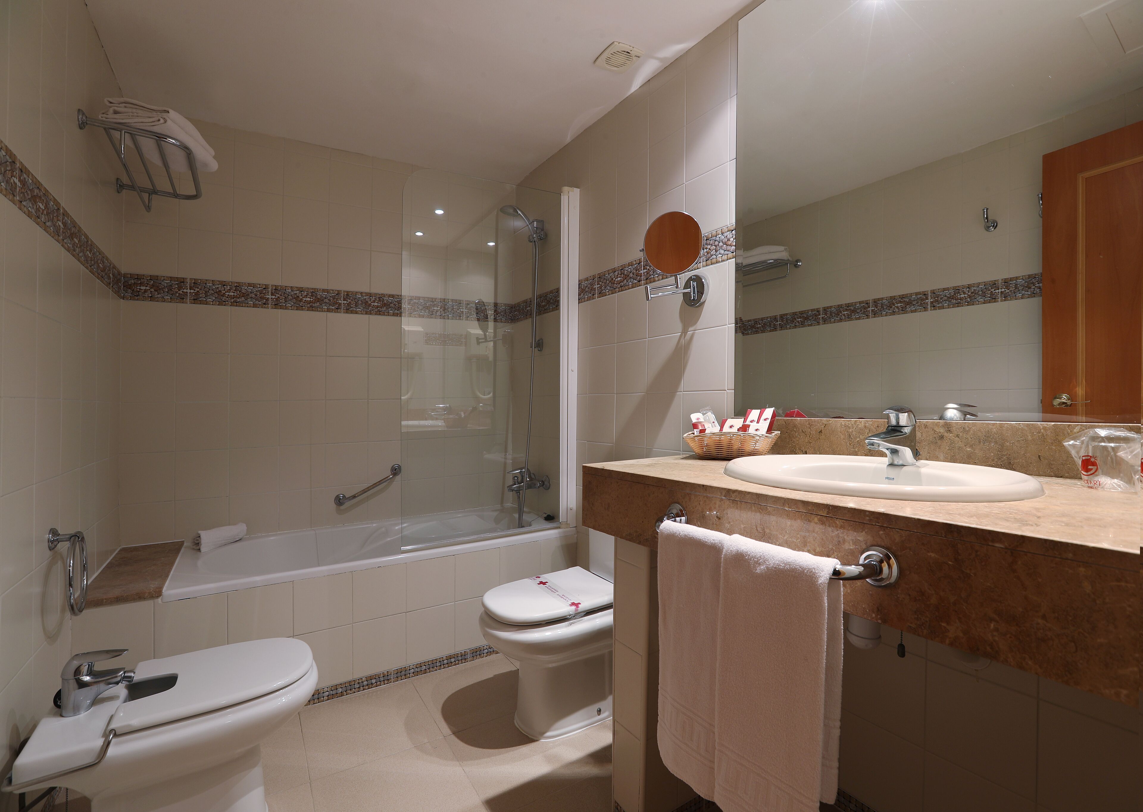 Une salle de bain avec une douche à parois de verre, des toilettes, un lavabo avec un miroir et un porte-serviettes.