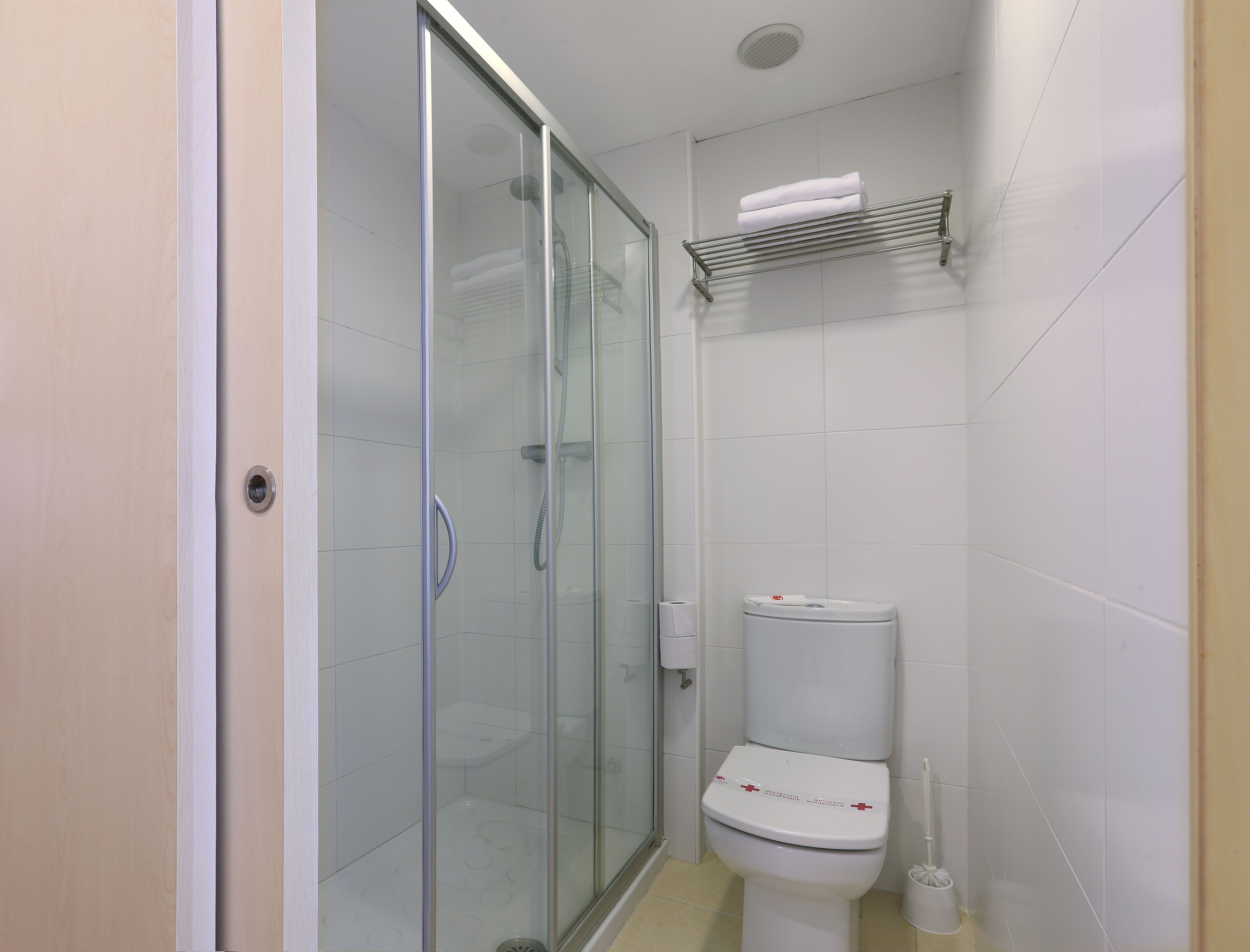 A bathroom with a glass-enclosed shower, a toilet, and a towel rack.