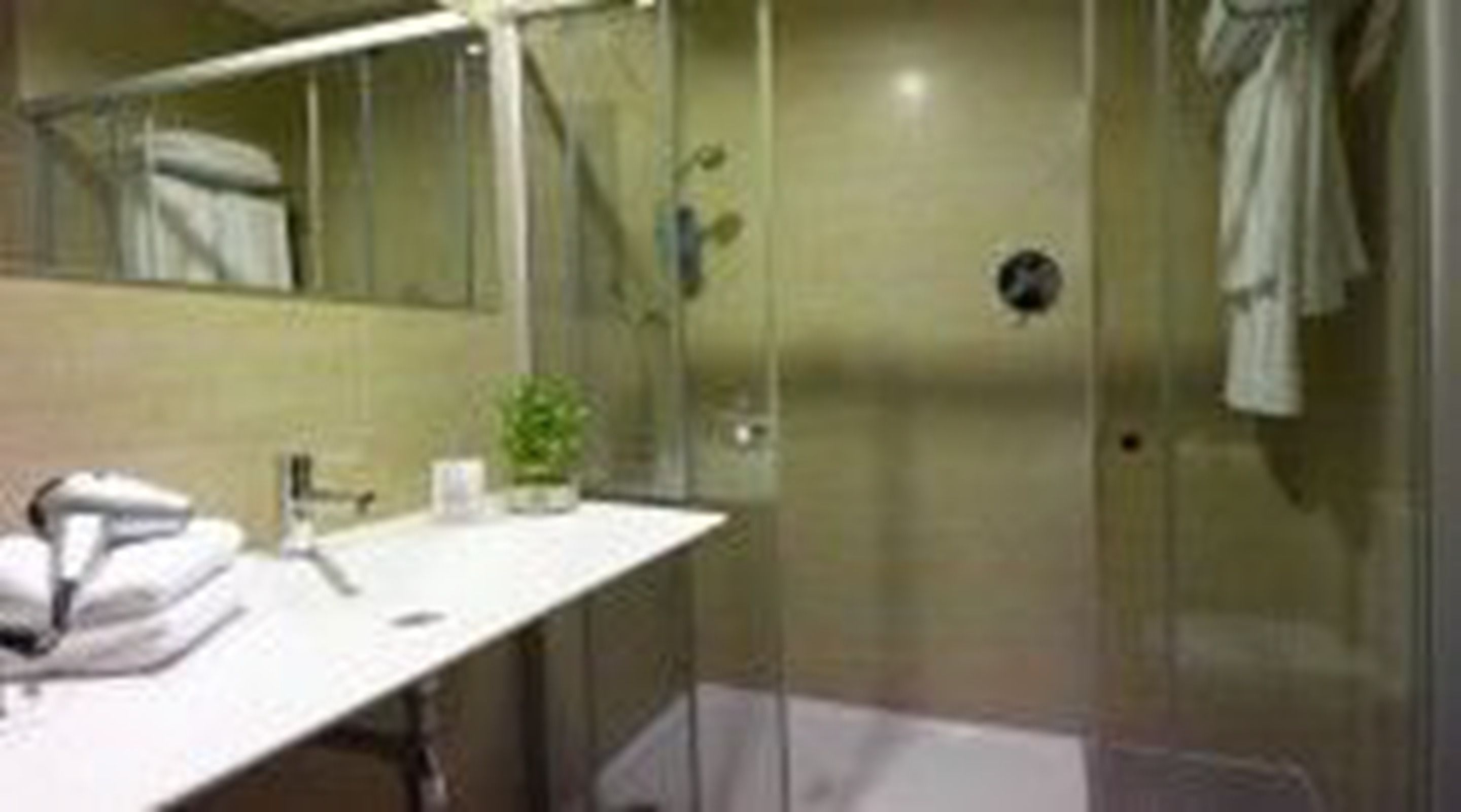 A bathroom with a glass shower enclosure, a white sink, and a mirror.