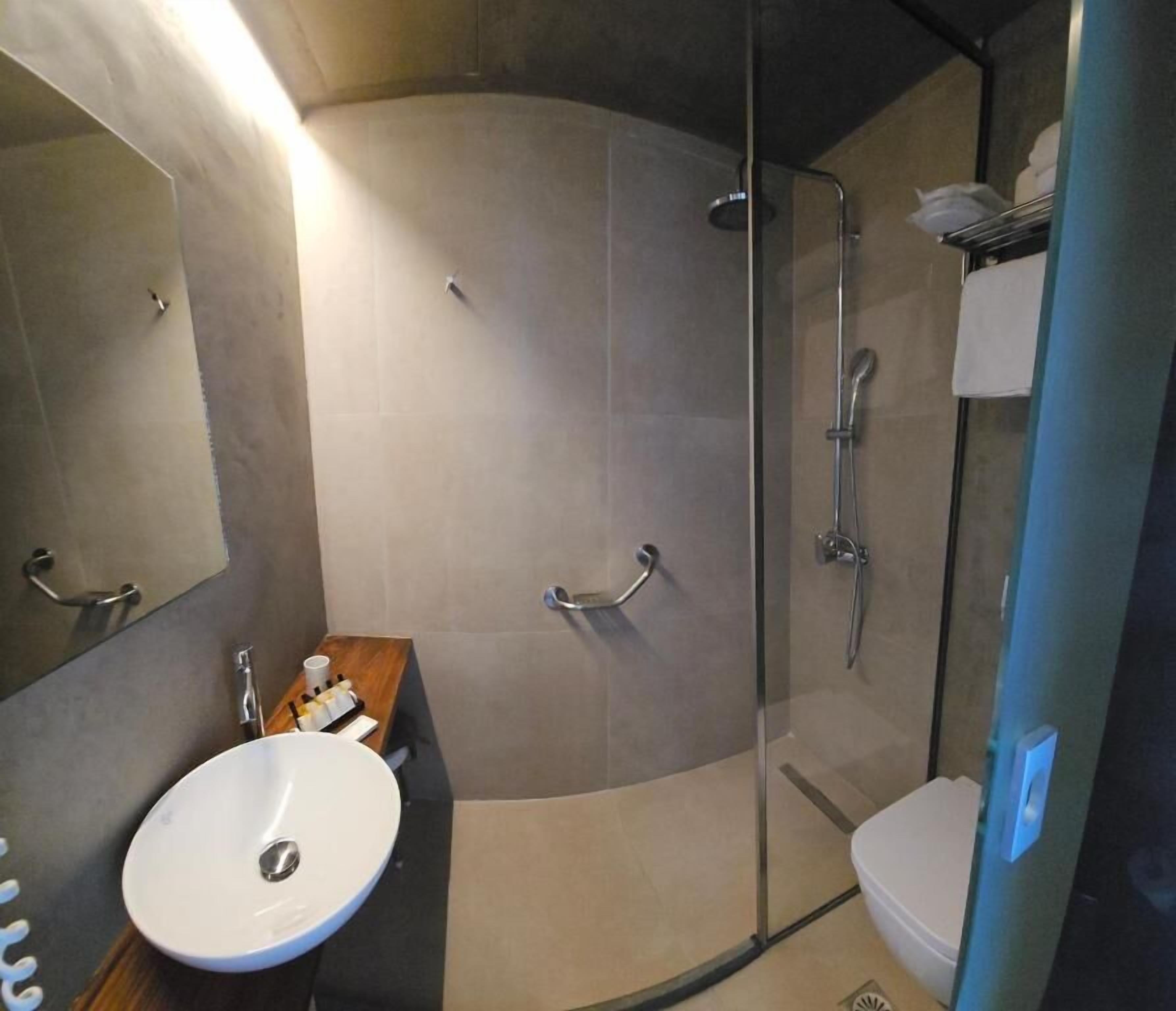 A modern bathroom with a glass-enclosed shower, a sink, and a mirror.