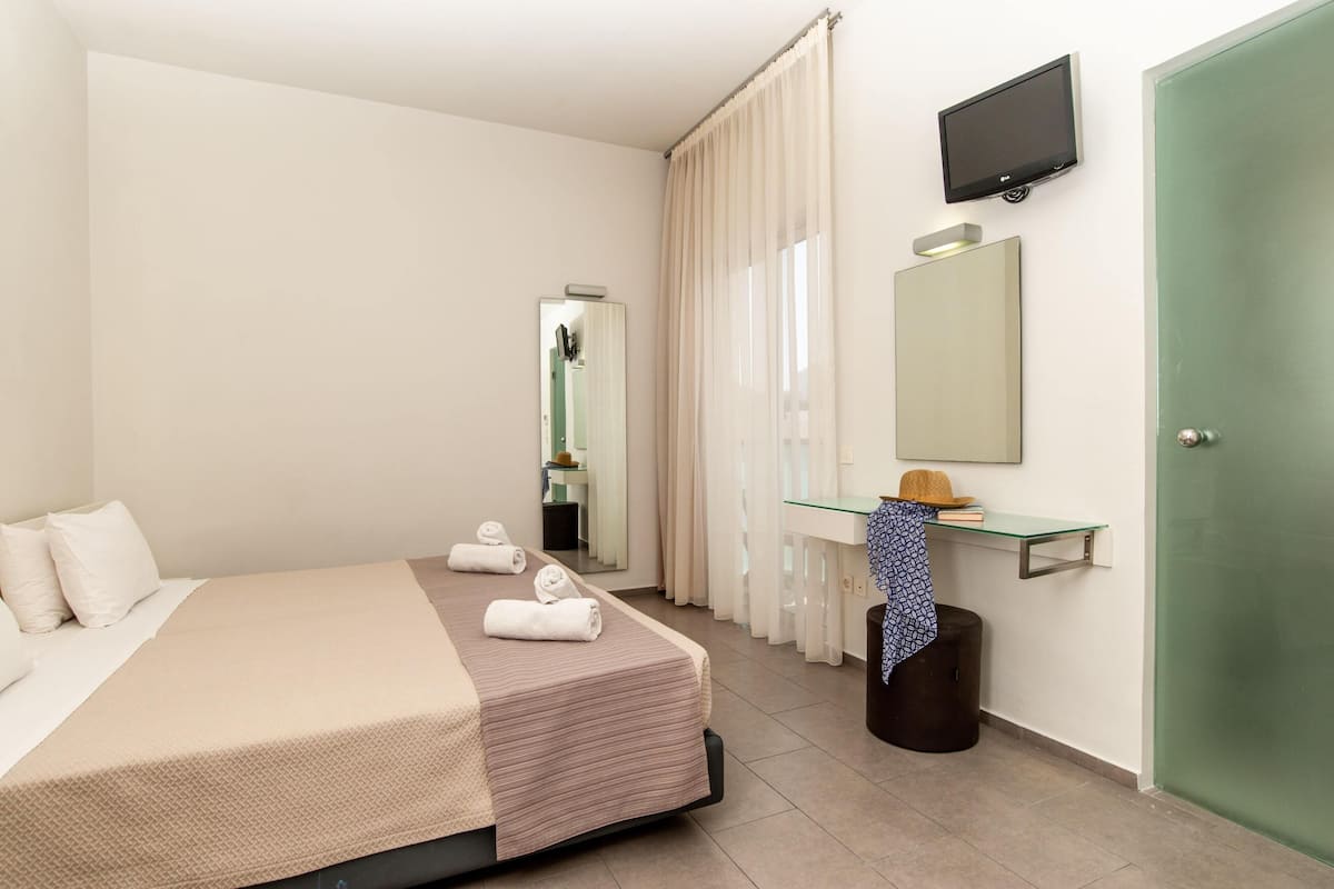 Ein Hotelzimmer mit einem Bett, einem Spiegel, einem Fernseher und einer grünen Tür.
