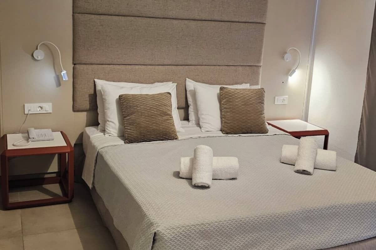 Ein ordentlich eingerichtetes Hotelzimmer mit einem großen Bett, zwei Nachttischen, einer Kopfteil und einer Hängelampe.