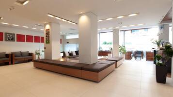 A spacious lobby with a large seating area, a reception desk, and a view of the outside.