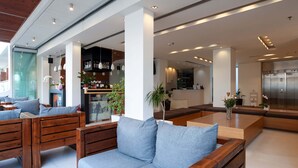 Un vestíbulo moderno con mobiliario de madera, una zona de bar y un ascensor a la vista.