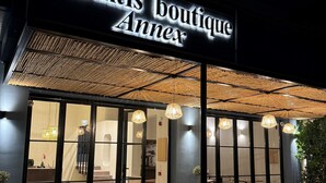 Exterior del Atlantis Boutique Annex con un diseño moderno, que presenta un gran letrero iluminado, un acceso cubierto y un área de estar visible en el interior.