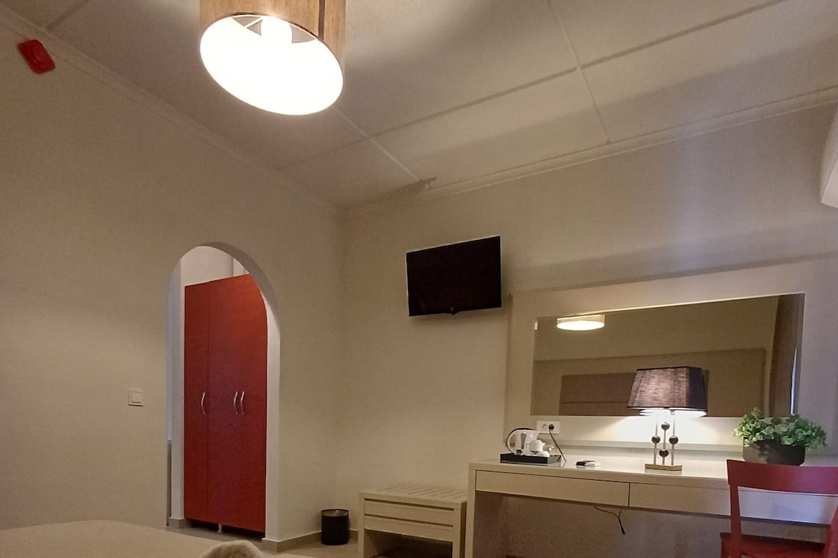 Ein Hotelzimmer mit Bett, Schreibtisch, Stuhl, Fernseher und Spiegel.