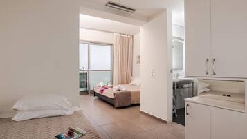 A hotel room with a bed, a small bedside table, a window with curtains, a bathroom with a sink and mirror, and a view of the city through the window.