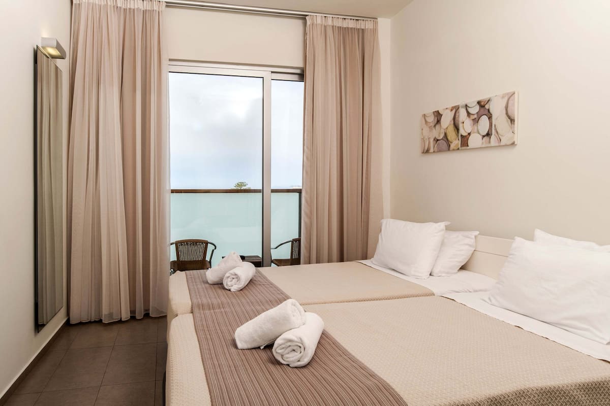 Ein Hotelzimmer mit Bett, Meerblick und Balkon mit Stuhl.