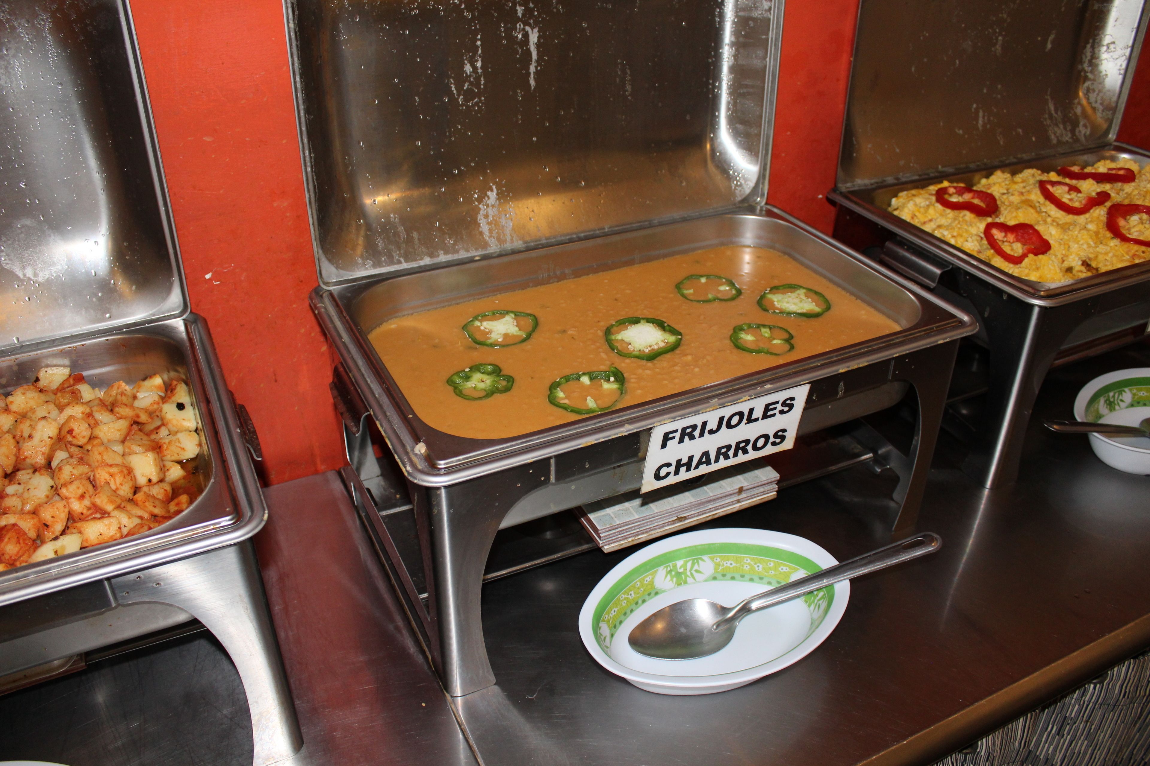 A buffet with labeled food stations including 'FRIJOLES CHARRROS'.