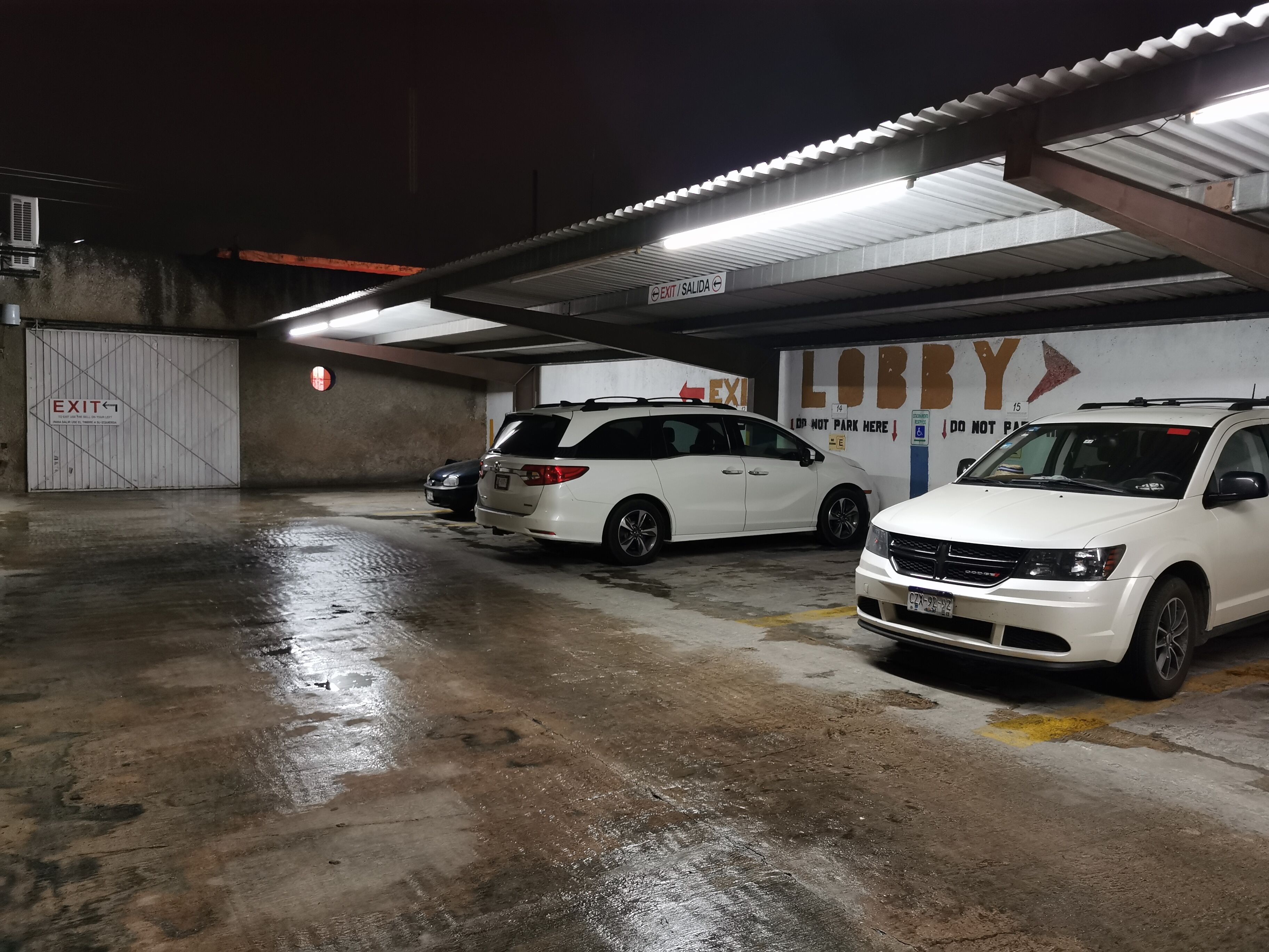 A parking garage with two white SUVs parked under a covered area.