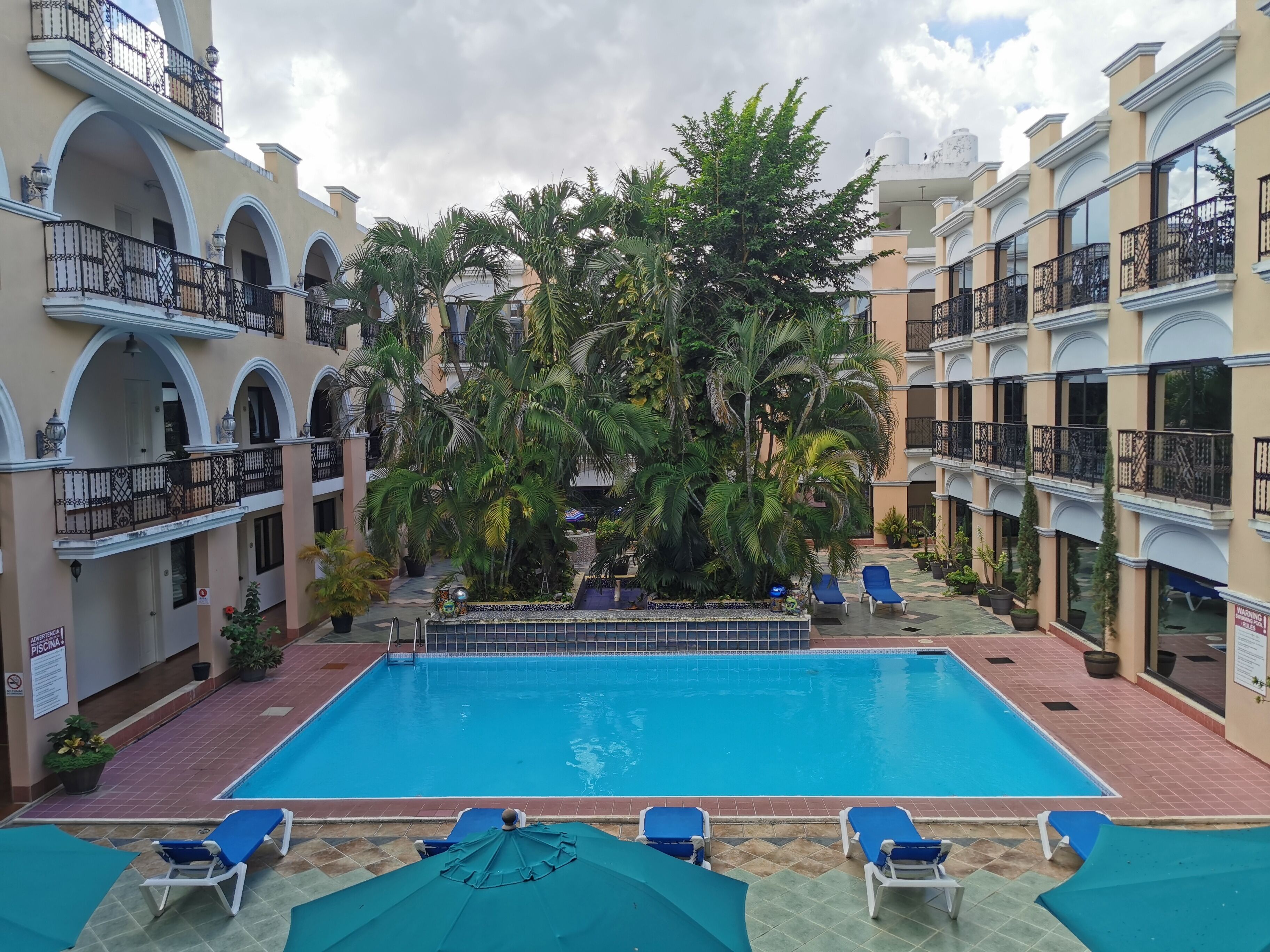 Una piscina rodeada de exuberante vegetación y varios balcones.