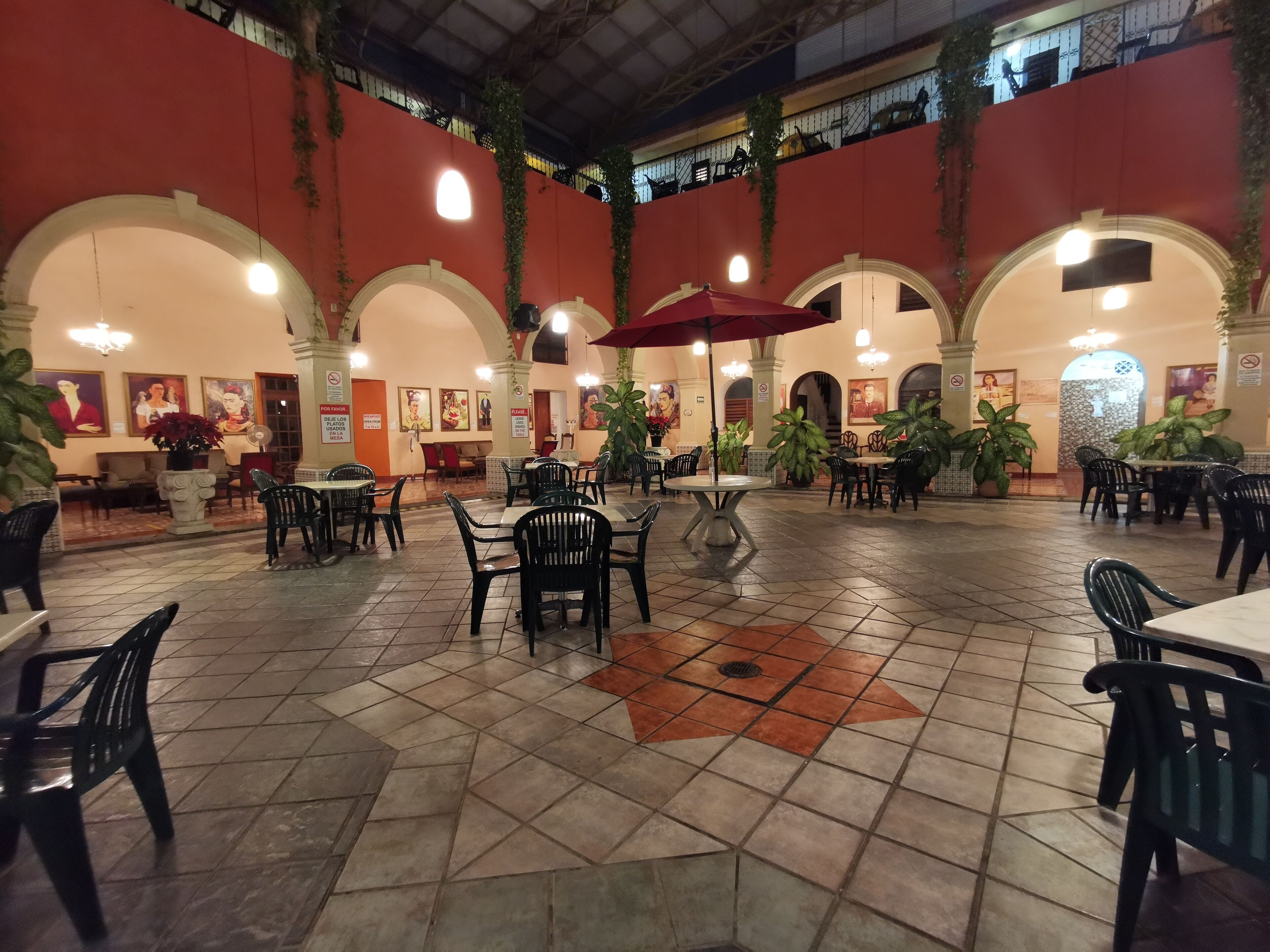 A spacious indoor dining area with multiple tables and chairs, featuring a tiled floor and arched ceilings.