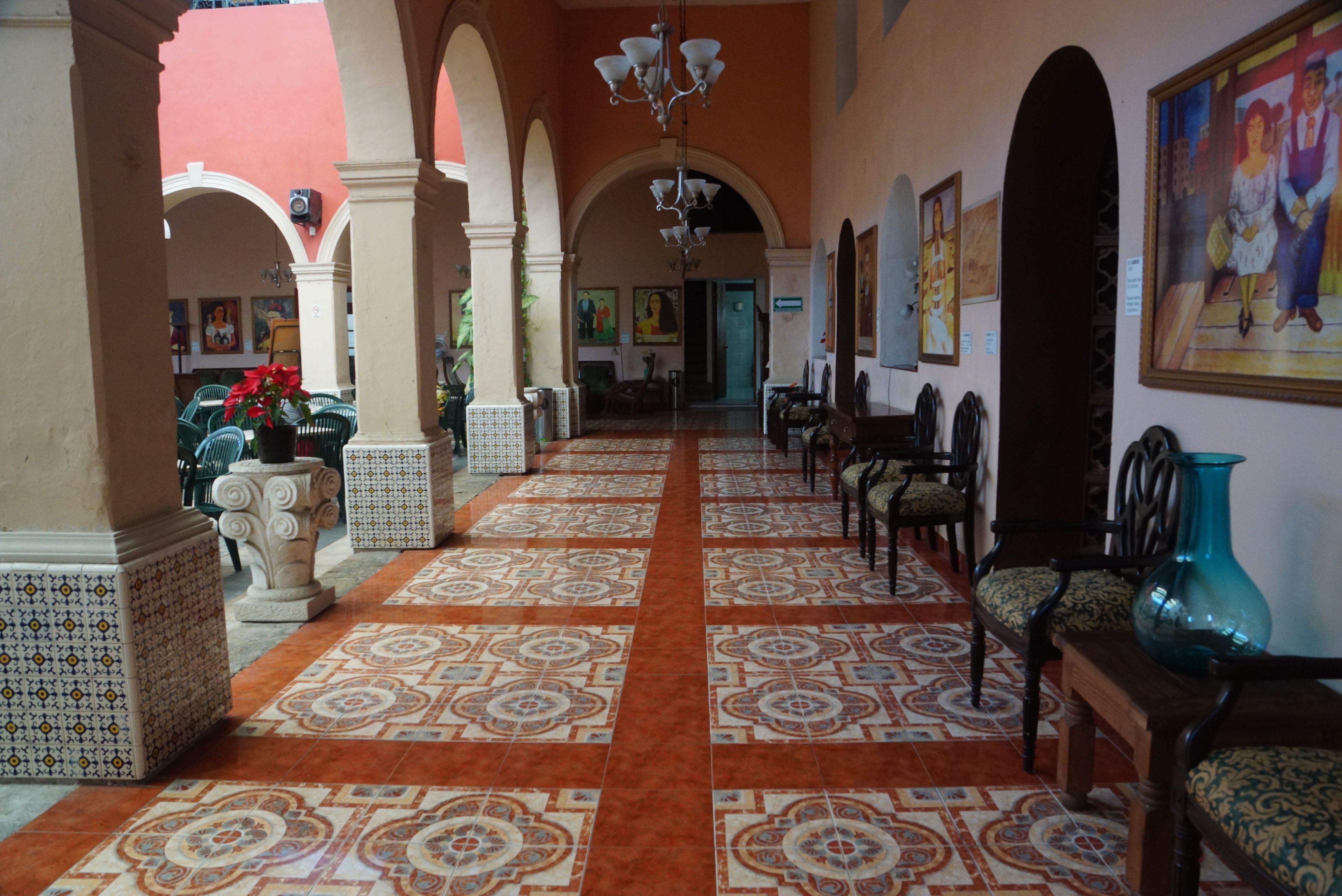 Un pasillo con suelo estampado, columnas y sillas.