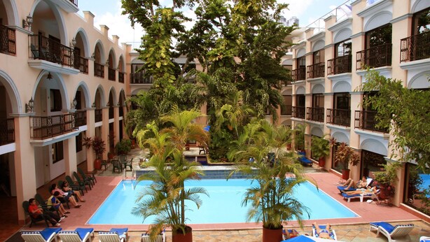 A hotel courtyard with a swimming pool, lounge chairs, and potted plants. - Hotel Doralba Inn (Mérida)