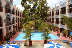 Un patio de hotel con piscina, sillones de descanso y plantas en macetas.