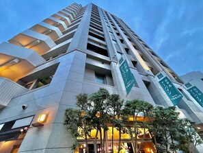 A modern hotel building with multiple floors, large windows, and green signage indicating it is a hotel. - Urbain Hiroshima Executive (Hiroshima)