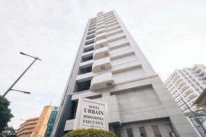 Een hoog gebouw met een bord voor Hotel Urban Hiroshima Executive.