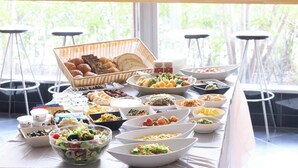 A buffet table with various food items and a basket of bread. - Urbain Hiroshima Executive (Hiroshima)
