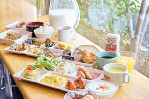 Een ontbijtbuffet met diverse gerechten, een melkkannetje en een vruchtensap.