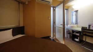 A hotel room with a bed, a bathroom with a sink and mirror, and an air conditioning unit. - Urbain Hiroshima Executive (Hiroshima)