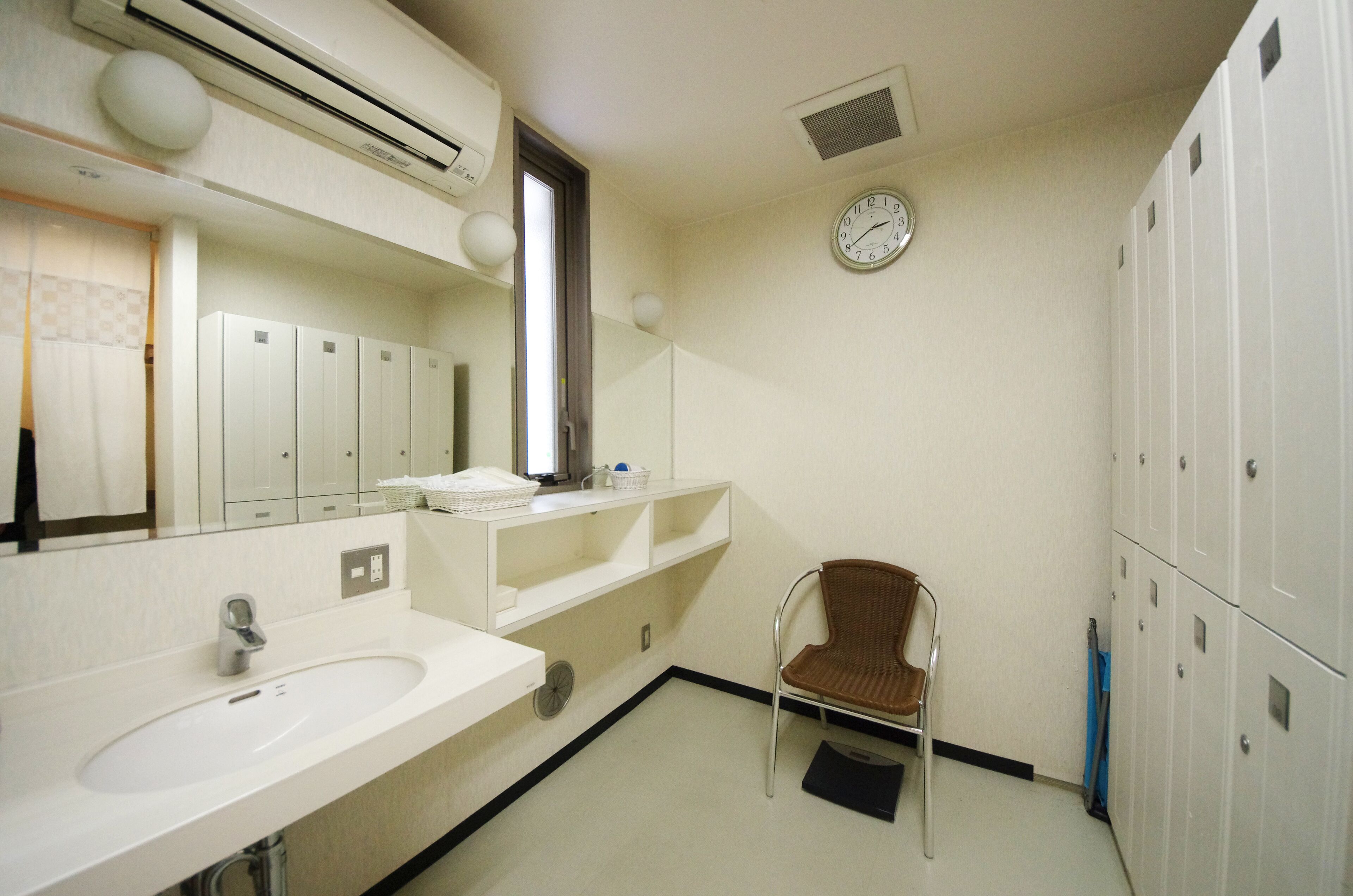 A bathroom with a sink, mirror, and a clock on the wall.