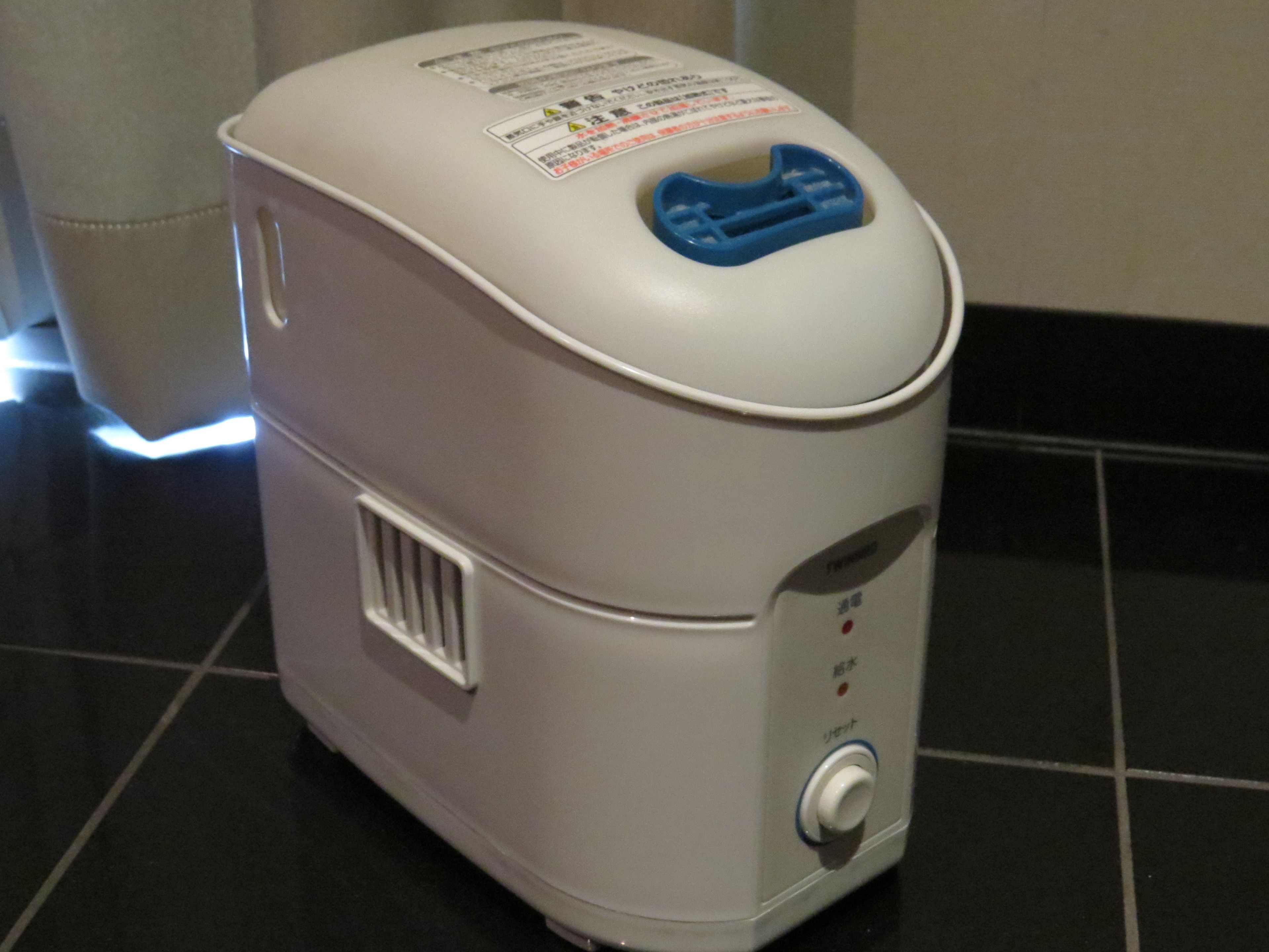 A compact, white portable heater with a blue control panel and a vent on the side.