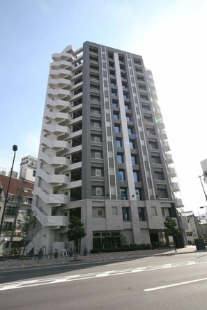 Een hoog, modern appartementencomplex met een opvallend zigzag-balkondesign, meerdere verdiepingen en een strakke, stedelijke omgeving.