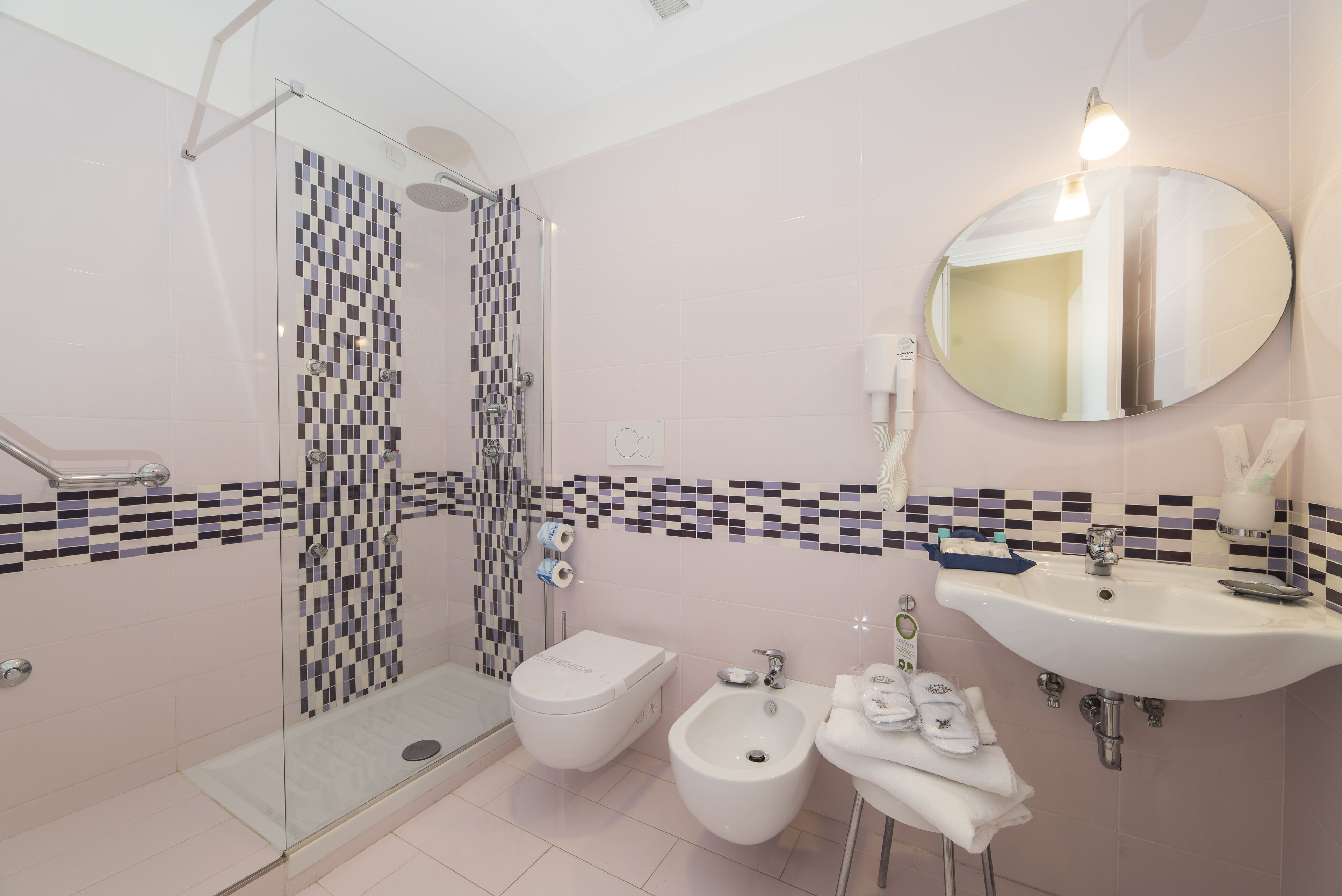 A modern bathroom with a glass shower enclosure, a bidet, a sink, and a mirror.