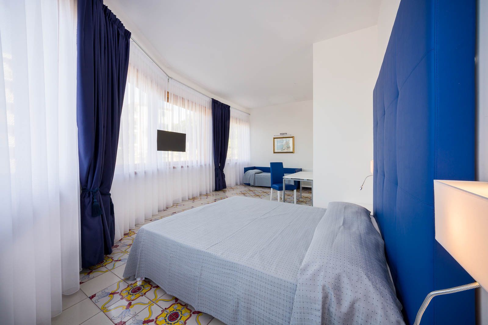 Una camera d'albergo con un letto, una scrivania, una sedia e una TV.
