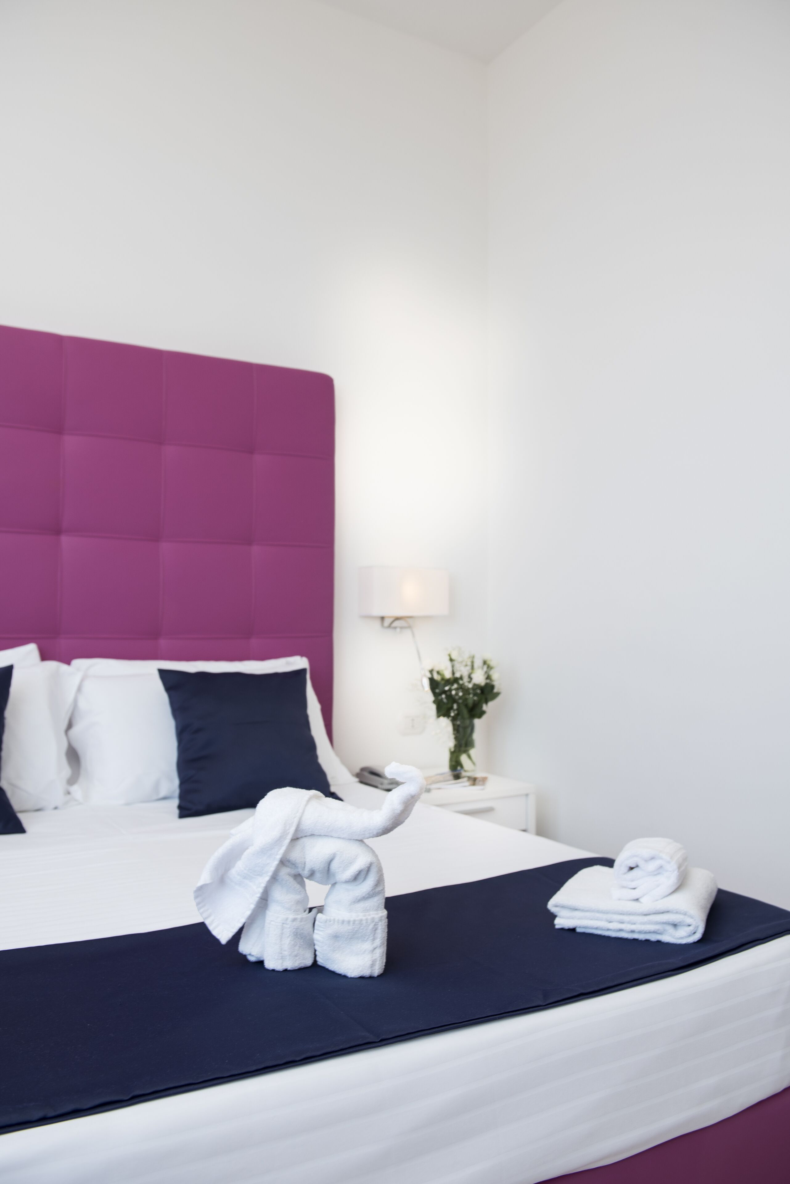 A hotel room with a bed, a nightstand, a lamp, and a decorative elephant figure.