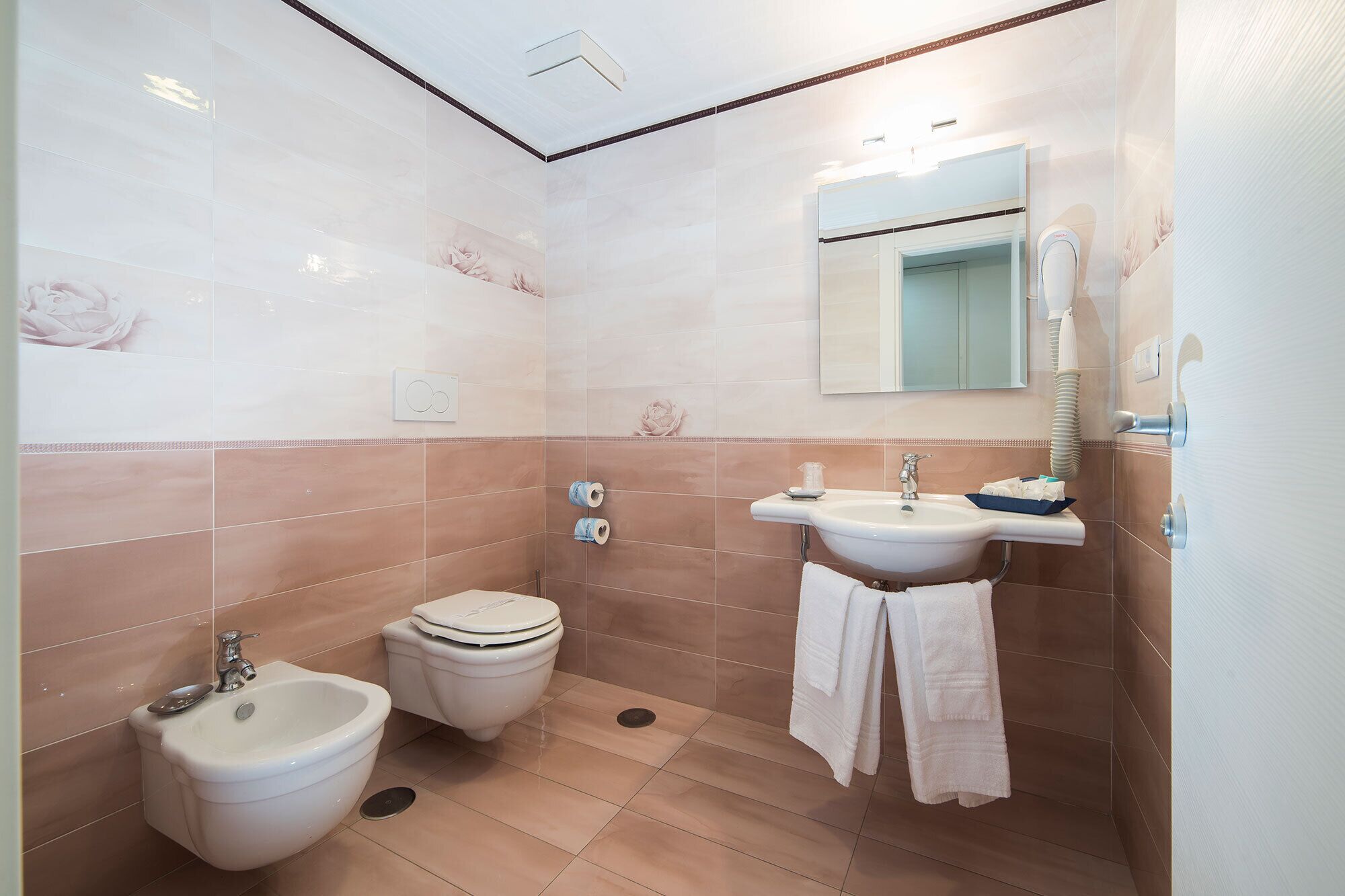 A bathroom with a bidet, toilet, sink, and towel rack.