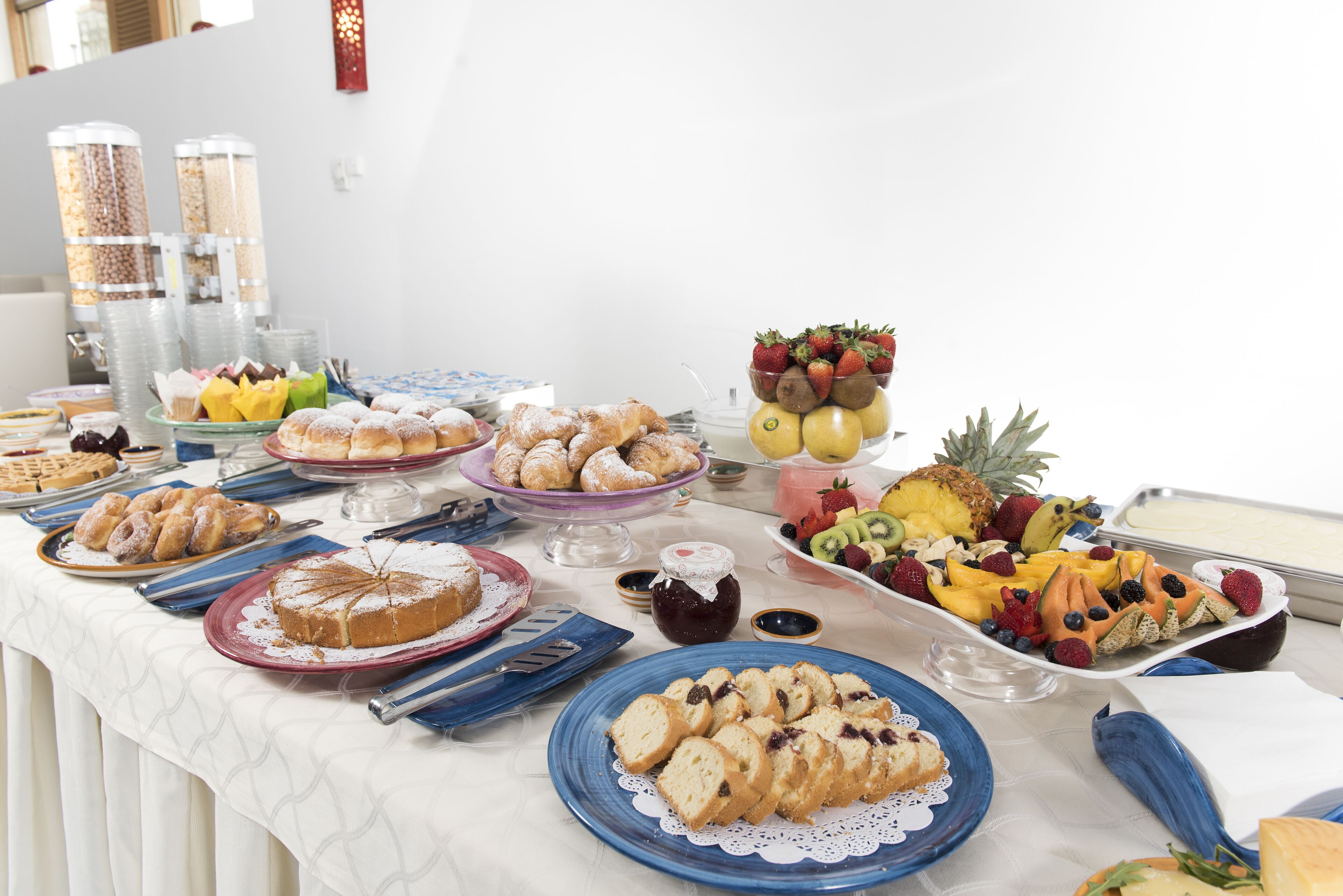 Una mesa de buffet con diferentes opciones de comida, incluyendo pasteles, frutas y salsas.
