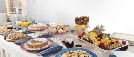 Una mesa de buffet con diferentes opciones de comida, incluyendo pasteles, frutas y salsas.