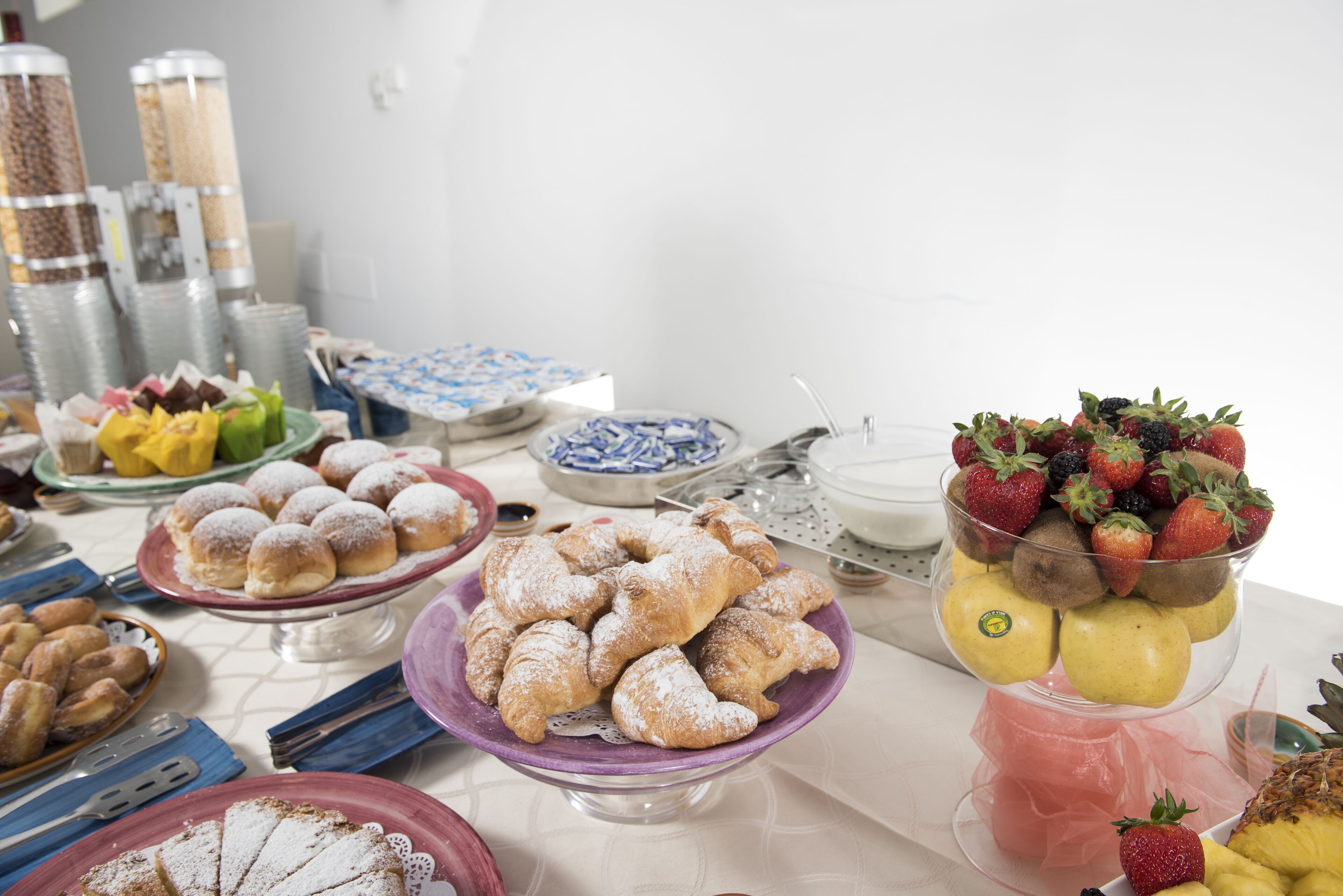 Een buffet met diverse gerechten, waaronder gebak, fruit en desserts.