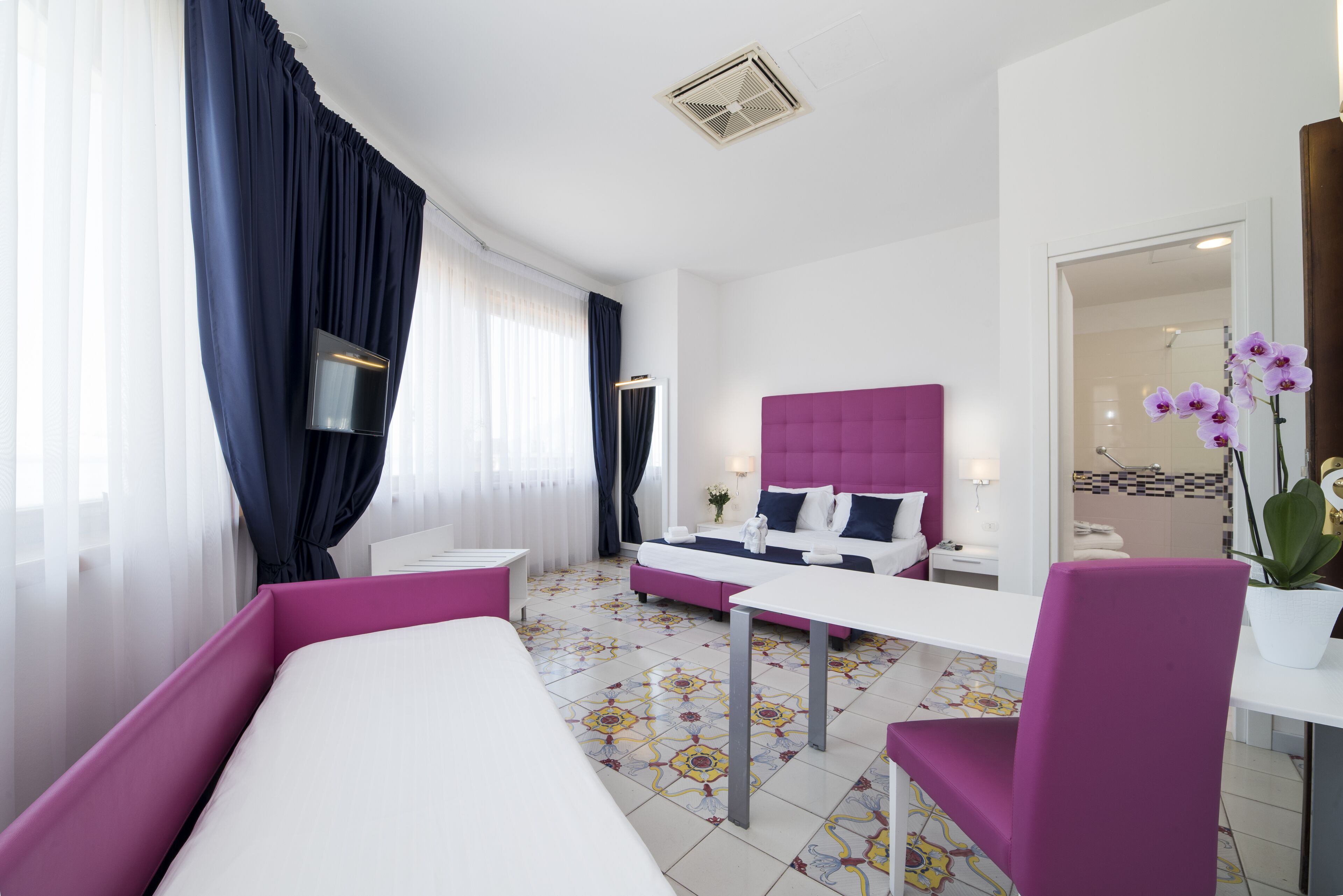 Una habitación de hotel moderna con una cama grande, un escritorio y una zona de estar.