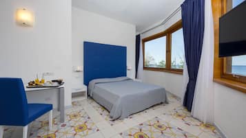 Una habitación con cama, escritorio con desayuno, televisor y ventana con cortinas.