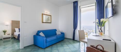 Una habitación moderna con un sofá azul, un escritorio blanco, un bolso de cuero marrón y un ventilador de techo.