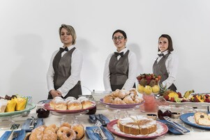 Tres camareras detrás de una mesa de buffet con diversos alimentos.