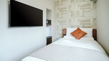 Quarto de hotel com cama, televisão de tela plana na parede, mesinha de cabeceira e cofre fixado na parede.