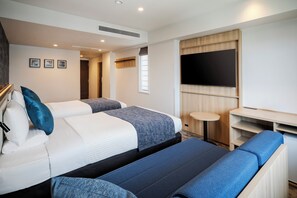 Habitación de hotel con dos camas, un televisor, una mesita y un sofá.