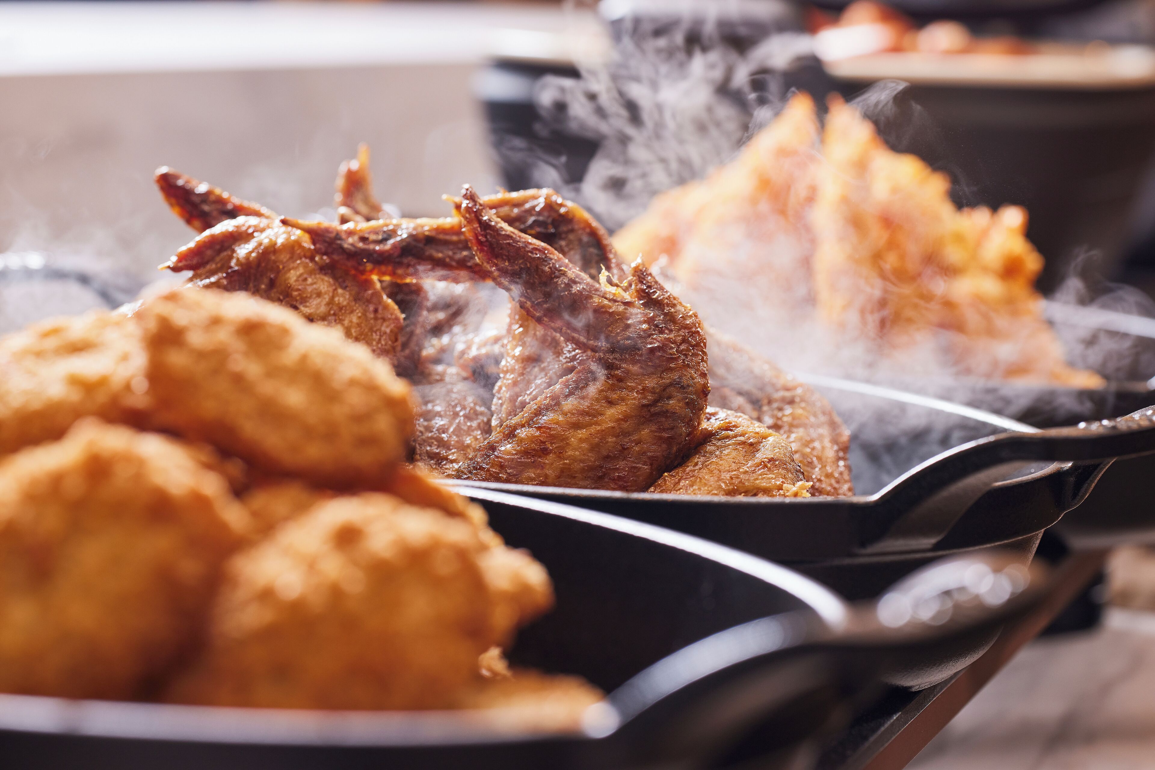 A close-up of a cooking pan with a roasted chicken and fried items.