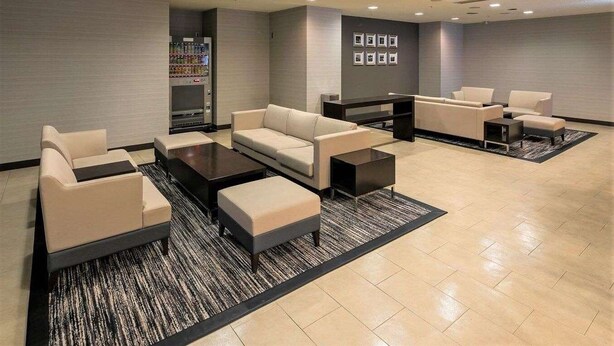 Un espace détente moderne avec des canapés, une table basse et un distributeur automatique.