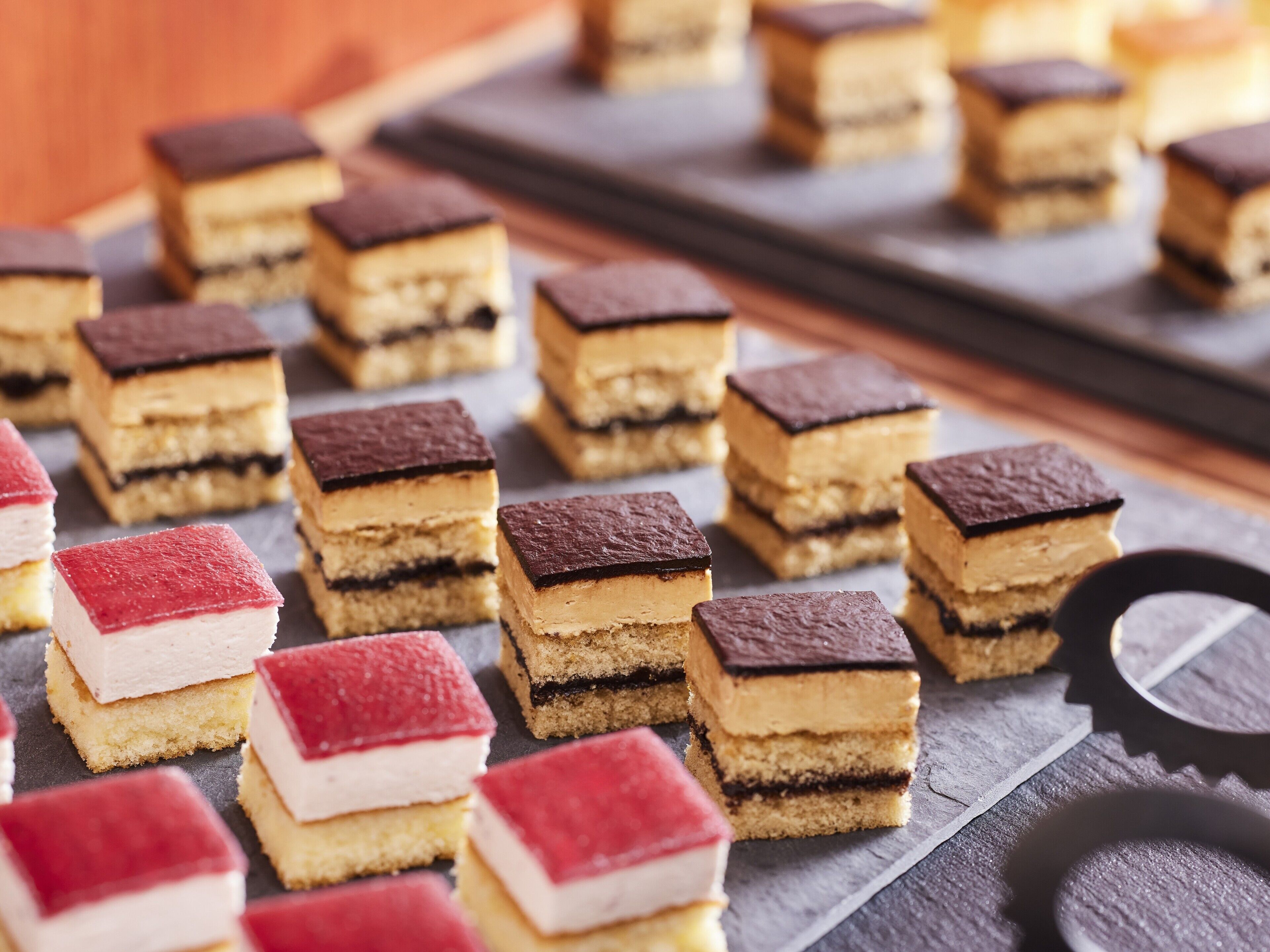 Una variedad de postres cuadrados sobre una superficie de pizarra.