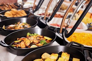 A buffet with various dishes including grilled chicken and rice.